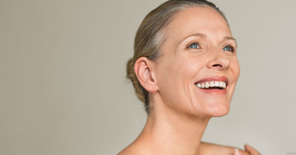 Mature woman smiling with neutral background (MODEL)