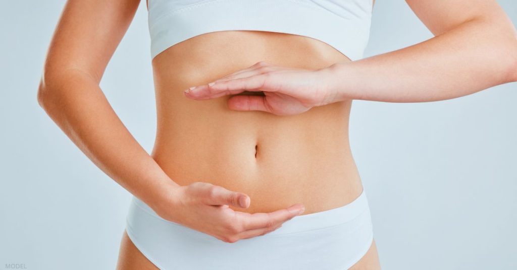 Woman with hands forming a circle over her abdomen (MODEL)