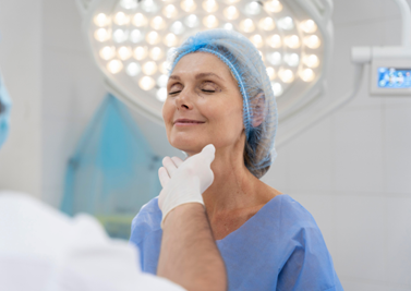 Stock model image of a person in surgical gown and cap being inspected by person with white gloves